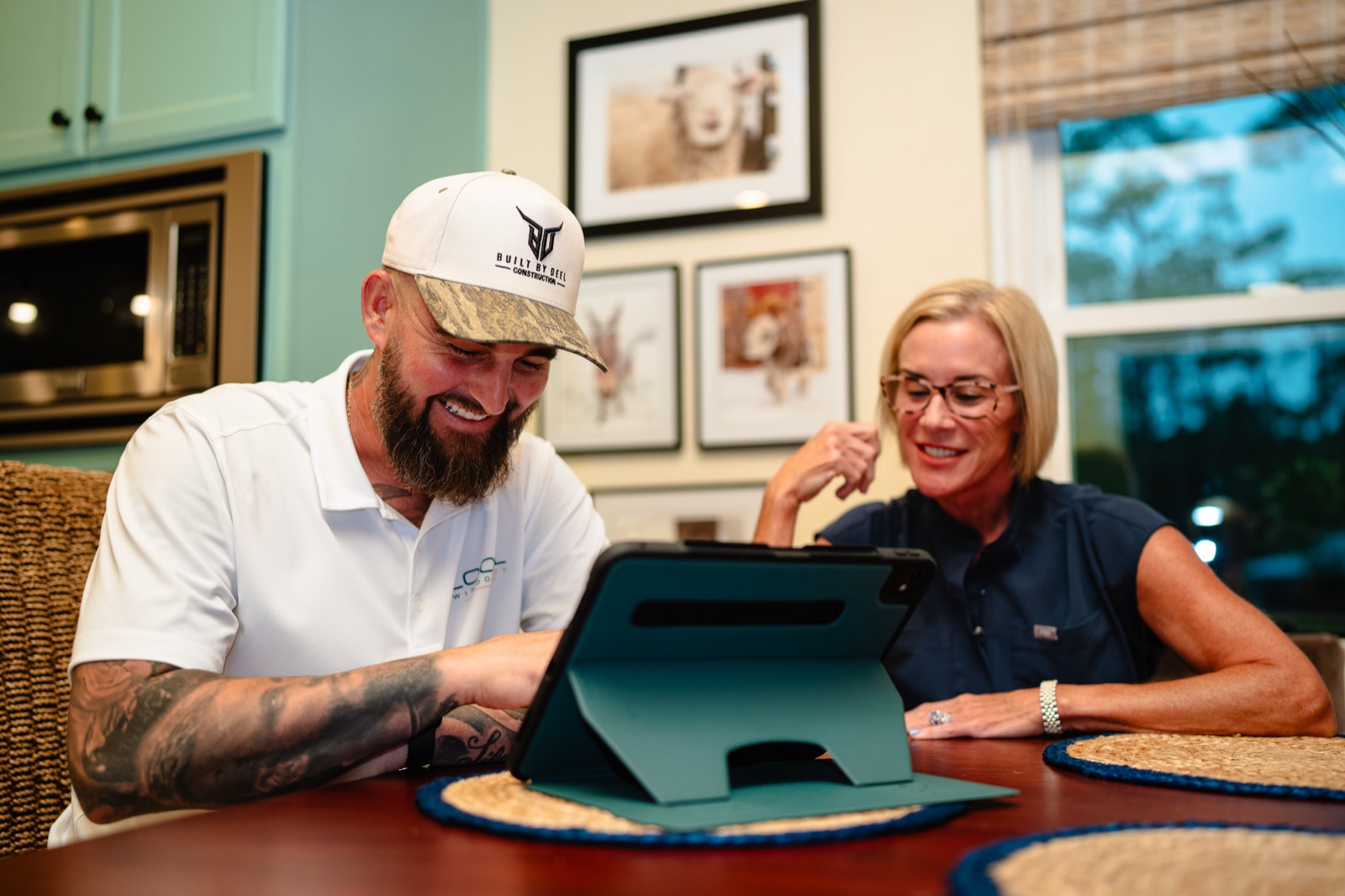 Local Window Guy owner reviewing window options on a tablet with a homeowner at her kitchen table
